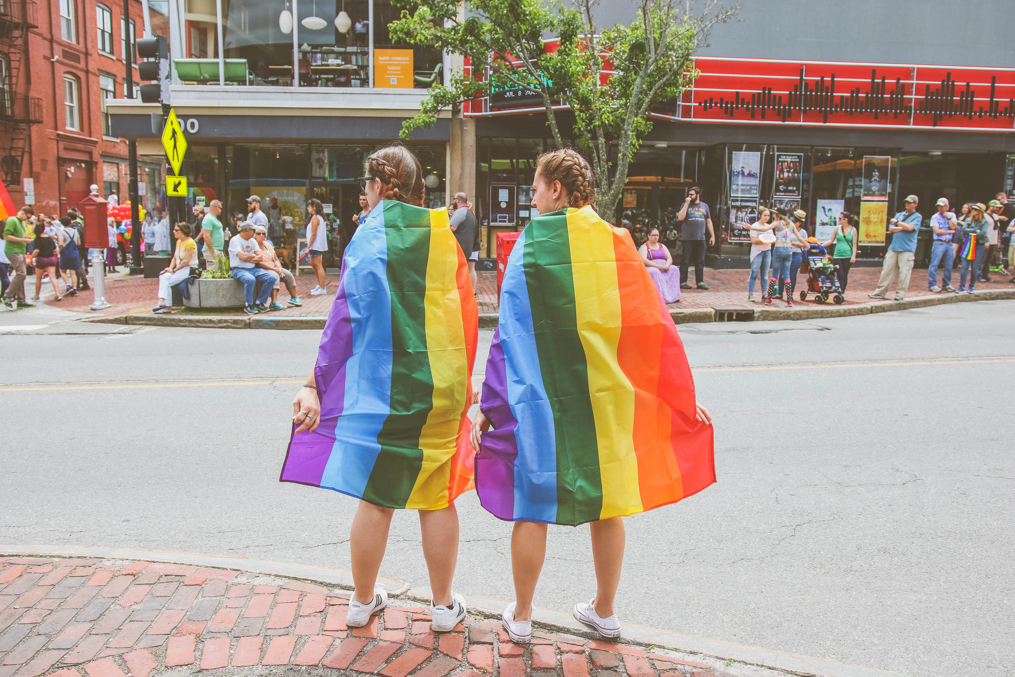 Foto de duas meninas enroladas em uma bandeira com as cores do arco íris