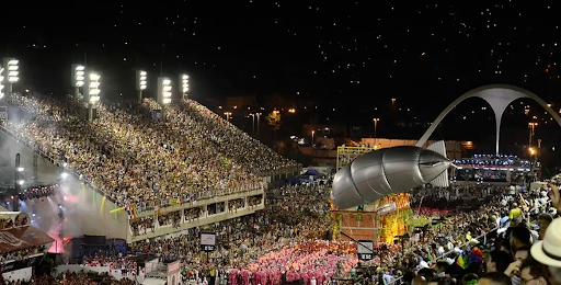 avenida Sapucaí apresentando desfile de escola de samba no carnaval do Rio de Janeiro com arquibancada a sua esquerda. 