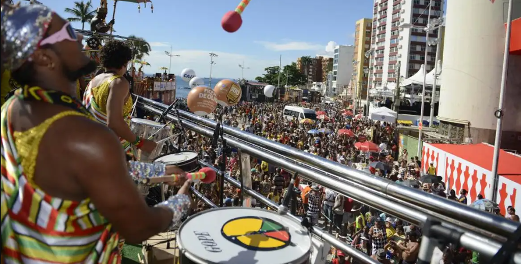 homem negro com camisa do olodum batucando um tambor em cima do trio elétrico.