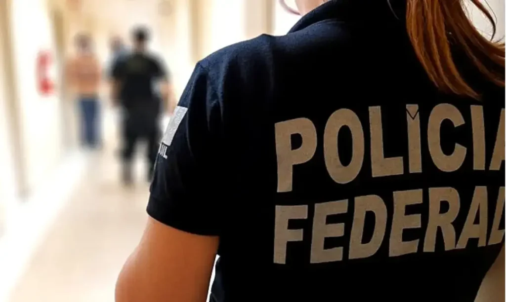 mulher de costas com uniforme da policia federal em um corredor claro
